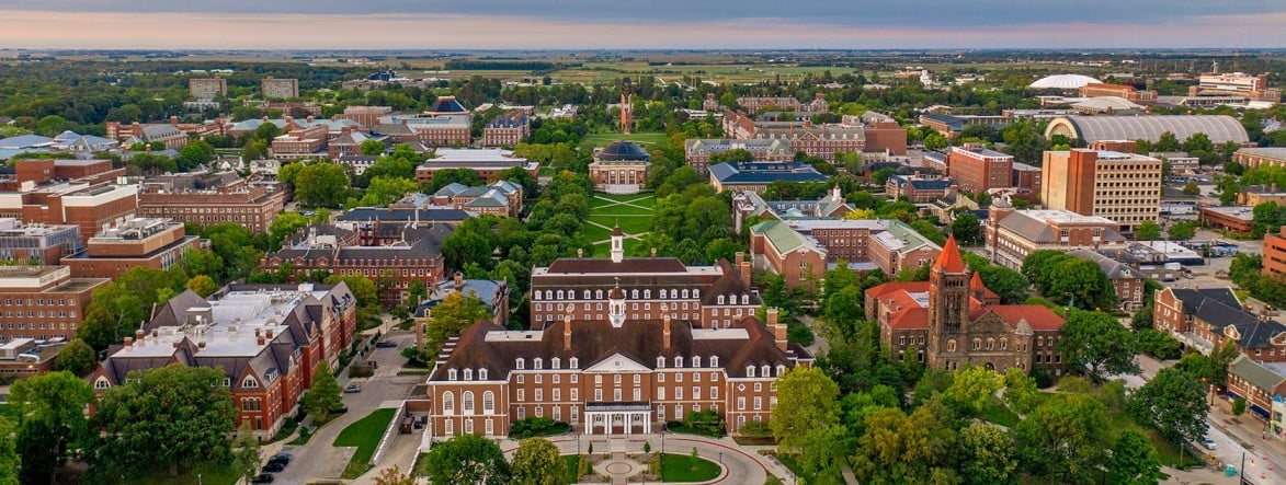 Aerial view of a historic university campus with brick buildings surrounded by residential neighborhoods and green trees